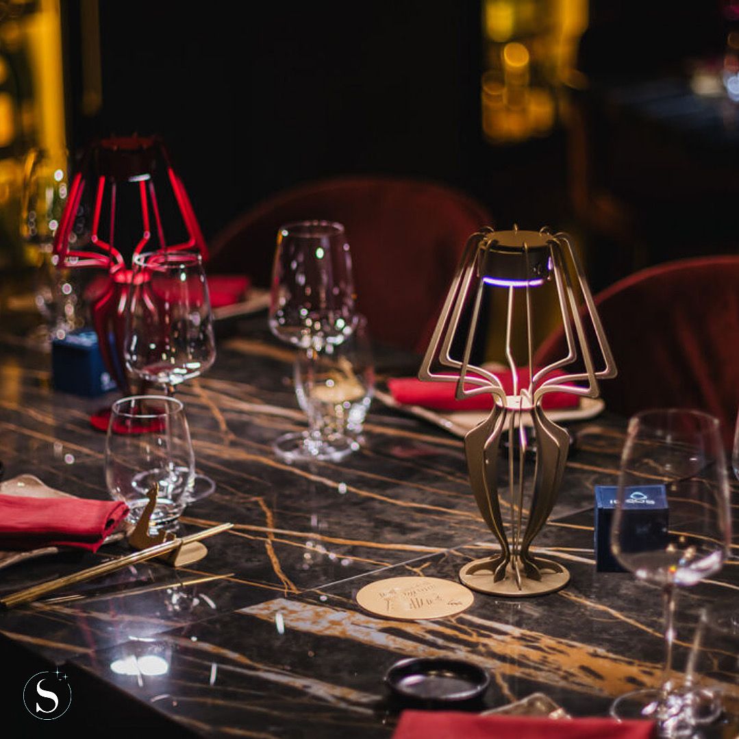 Gedekte tafel met marmeren blad, rood velours en gouden tafellamp in een high-end restaurantinterieur